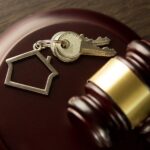 Młotek sędziego licytatora, klucz do drzwi na drewnianym stole. Koncepcja dla sądu, upadłości, podatków, hipoteki, aukcji, wykluczenia lub dziedziczenia nieruchomości